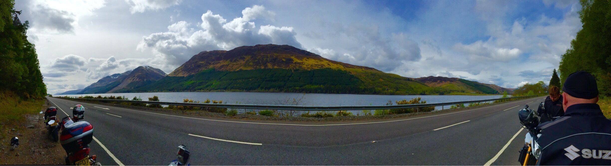 A road with a mountain in the background and a lake.
