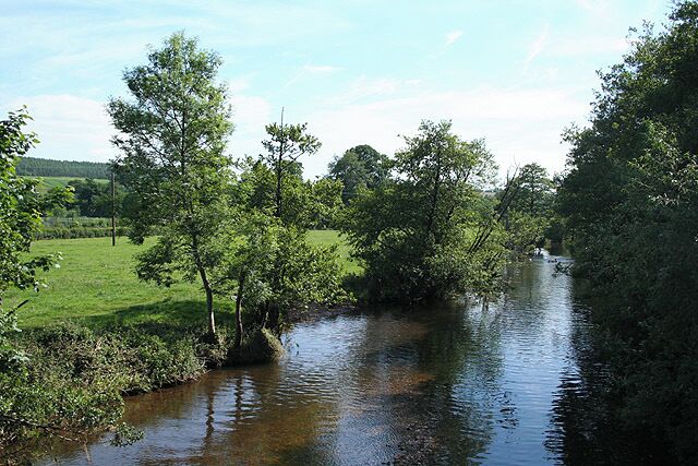 A river flowing through a green landscape with trees and open fields.