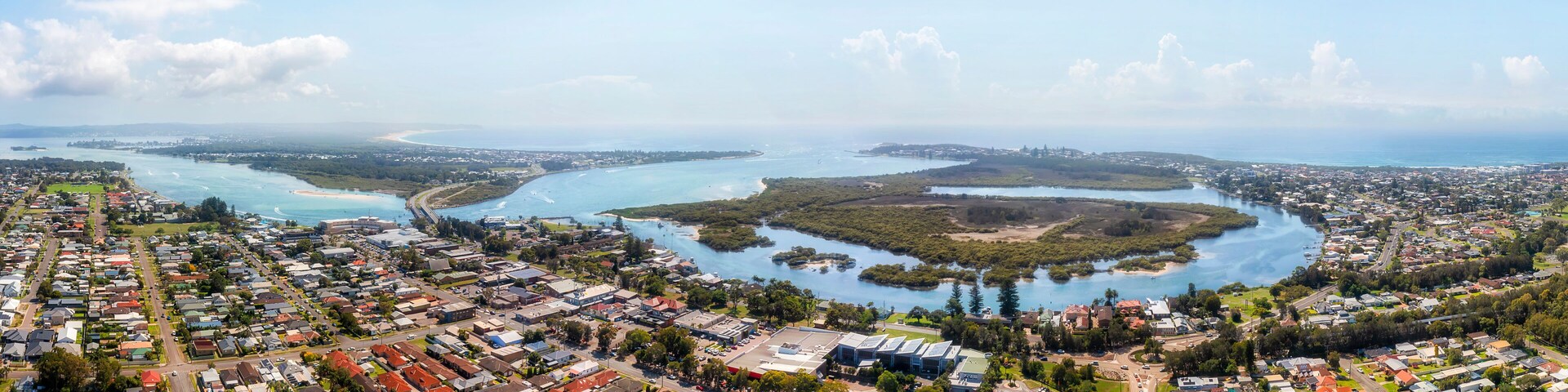 Uma vila costeira com um porto de recreio, áreas residenciais e uma baía com ilhas.