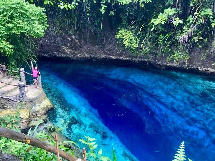 Una extensión de agua azul cristalina rodeada de vegetación exuberante y terreno rocoso.