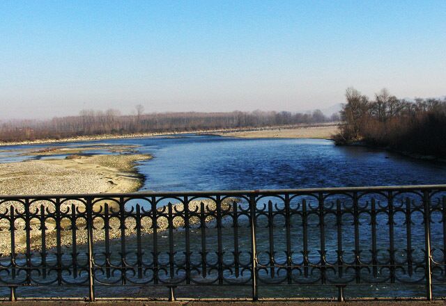 A river with a metal fence in the foreground and trees in the background.