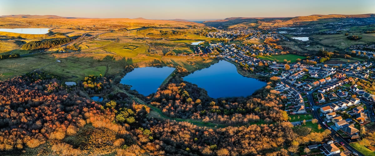 Vista panorámica de un pueblo con dos lagos, colinas circundantes y cielo despejado.