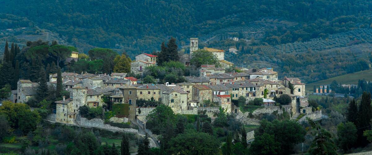 A historic village perched on a hillside with stone buildings and a prominent tower.