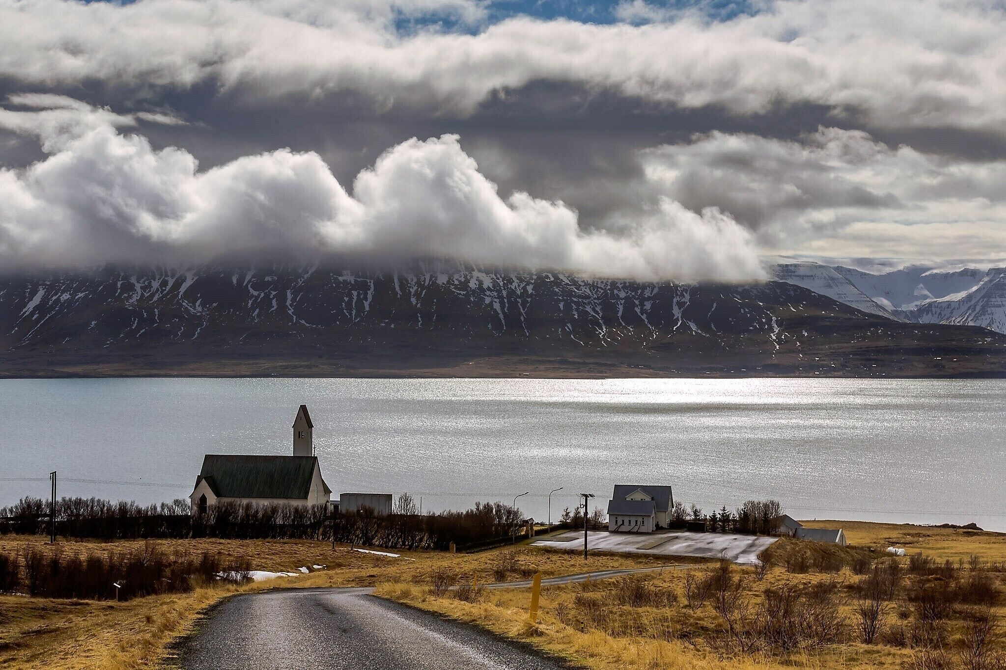 A church by a lake with mountains in the background.