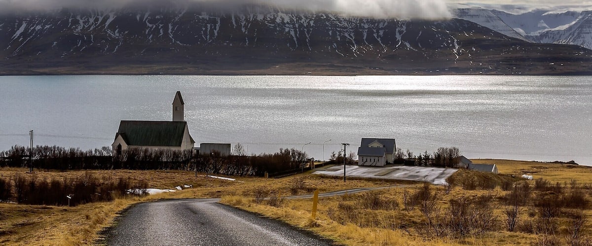 A church by a lake with mountains in the background.