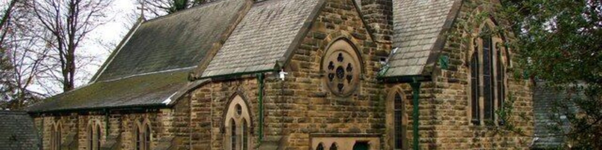 A stone church with a pointed roof and a bell tower.