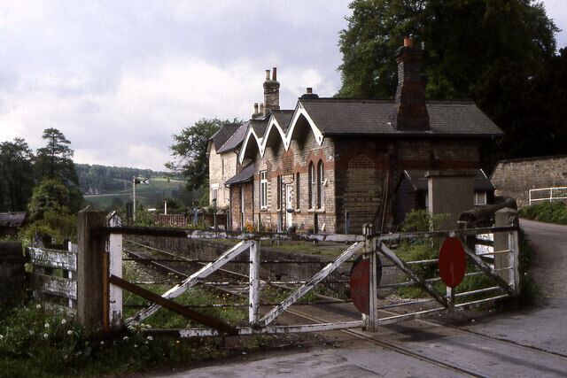 A railway station with a traditional stone building, a gated entrance, and a red stop sign.