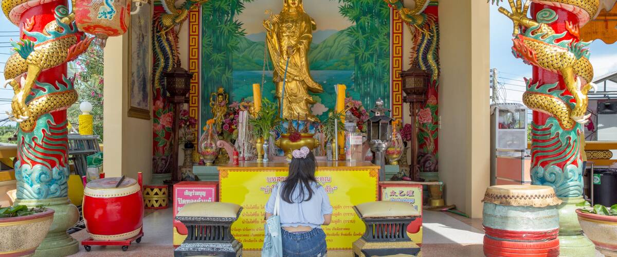 A temple with a large golden statue, colorful murals, and dragon decorations.