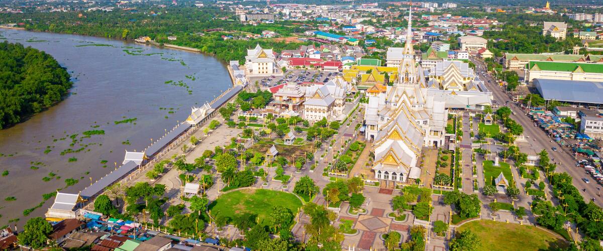 An aerial view of a city with a prominent temple complex, a river, and surrounding greenery.