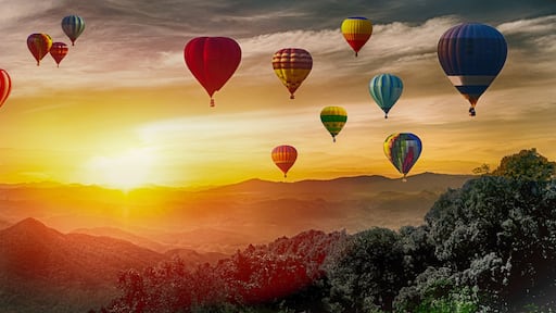Dramatic panorama of mountain with hot air balloons at sunset,Thailand.