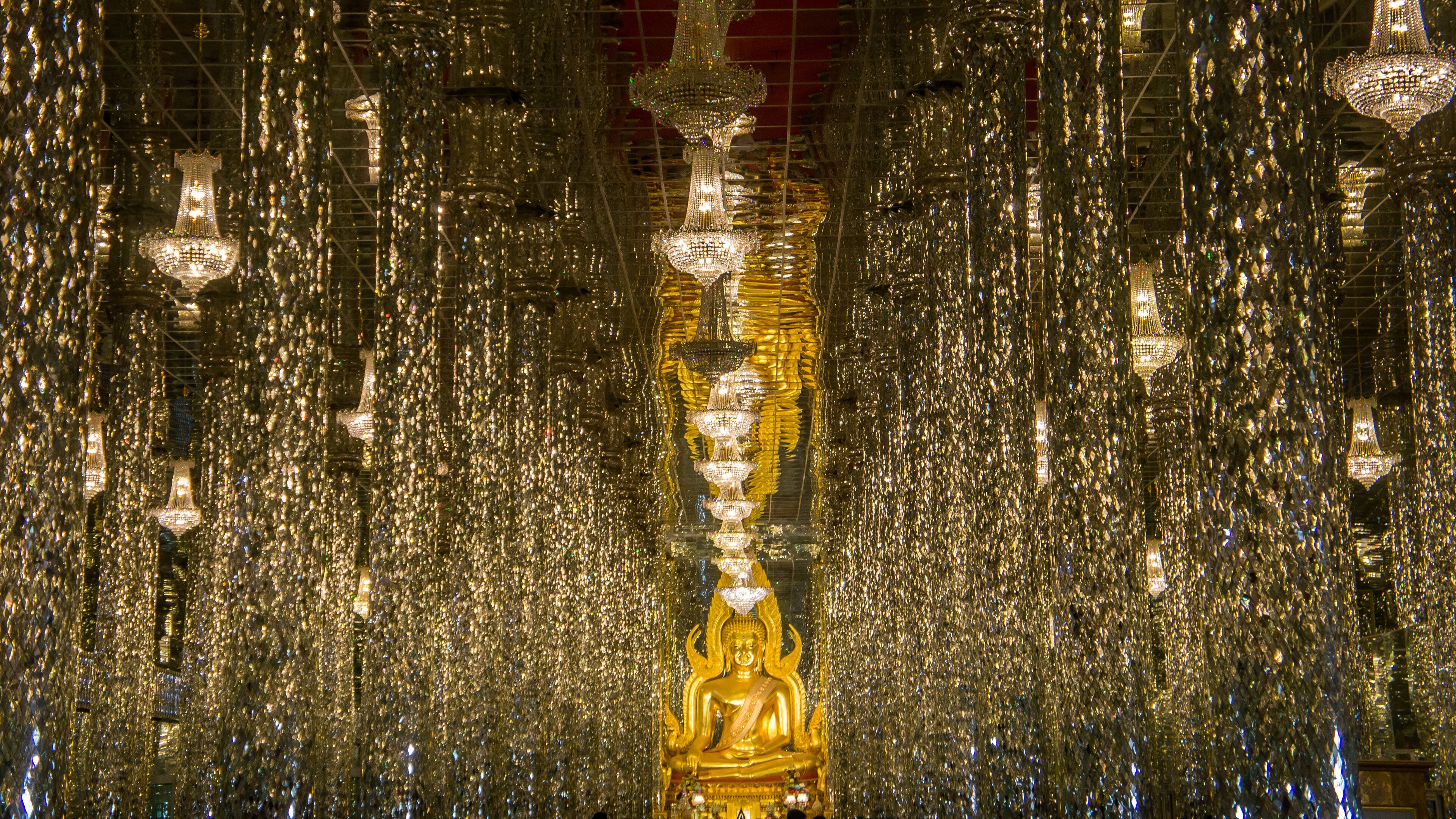 A golden Buddha statue surrounded by numerous hanging chandeliers.