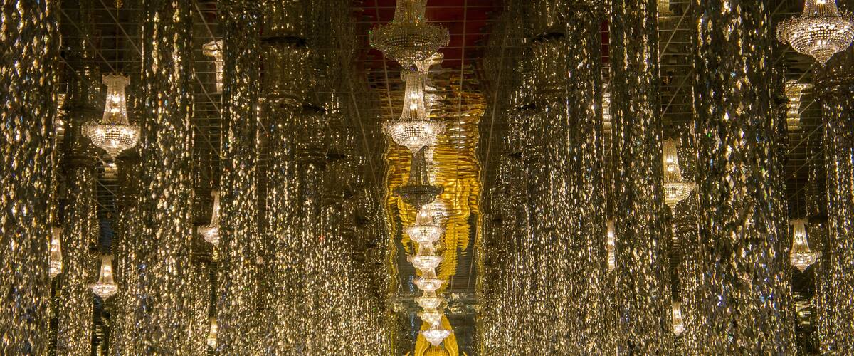 A golden Buddha statue surrounded by numerous hanging chandeliers.