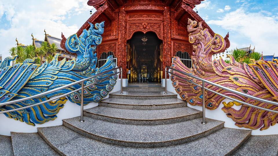 A temple with intricate blue and pink decorations and a staircase leading to the entrance.
