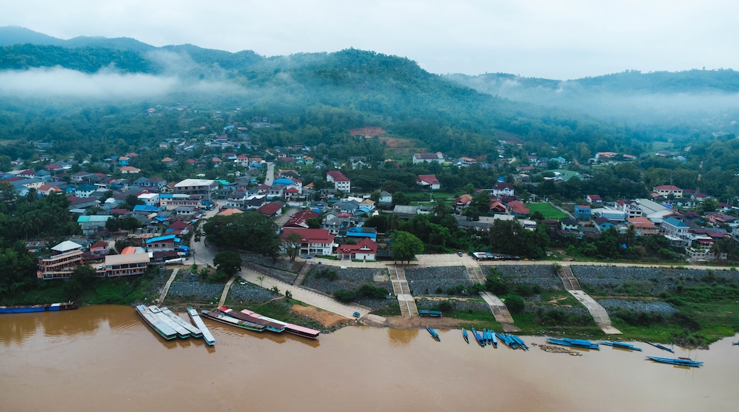 Aerial view of the mighty Mekong River winding from Chiang Khong, showing the vastness and beauty of the muddy waterway contrasting with the surrounding lush mountains and Laos villages.