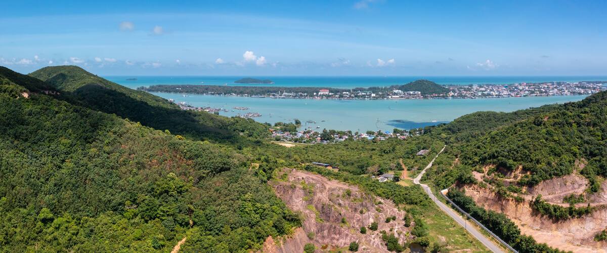 A coastal town with a bay, surrounded by hills and dense forest.