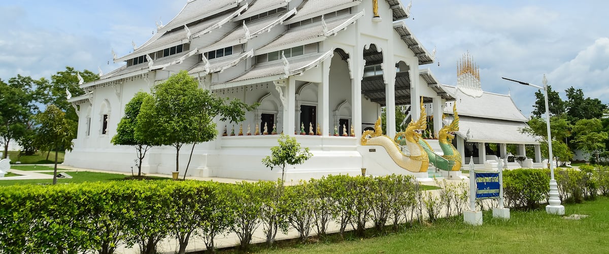 A white temple with a golden dragon statue in front.