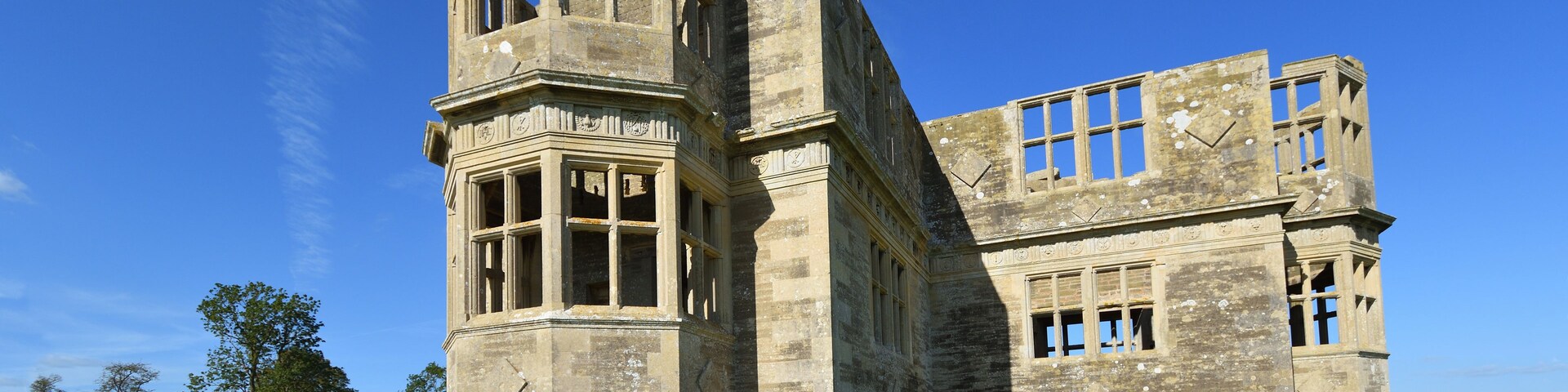 A large, historic stone building with a prominent tower, set against a clear blue sky.