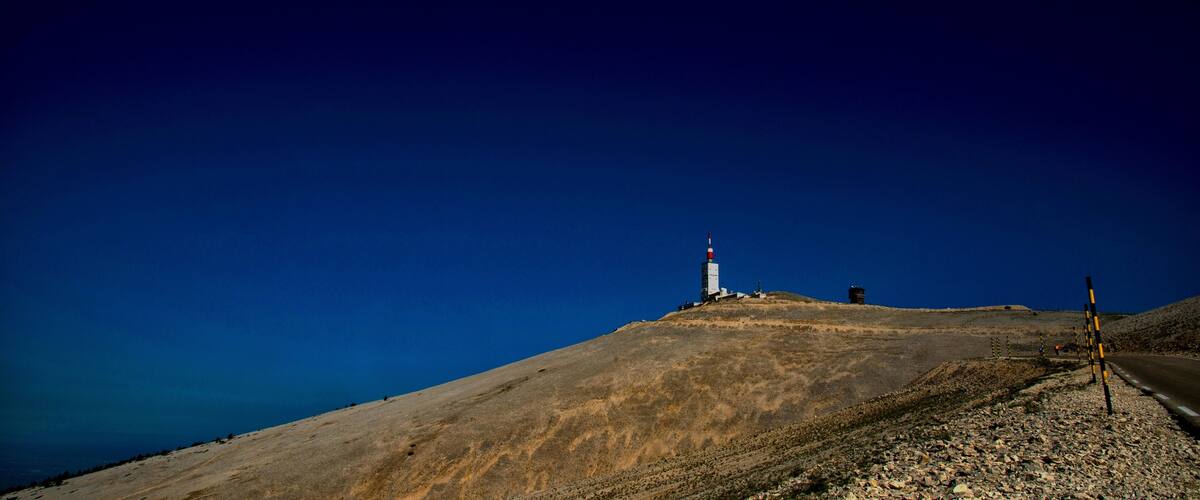 A lighthouse on a hill with a clear blue sky.