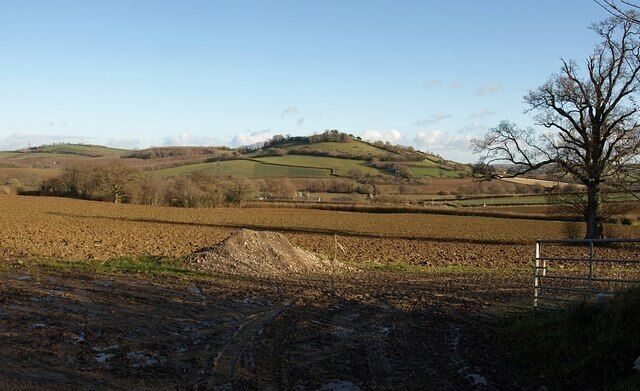 A rural landscape with rolling hills, a dirt path, and a metal gate.