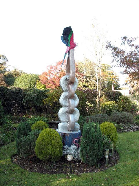 Memorial to Sammy. Sammy was a girl who was born with cerebral palsy. When she died, aged 13, a sculpture was put up in her memory beside the Kings Head public house > 1025721 which she used to like visiting, in the company of her parents. The sculpture was created from one single piece of wood by a wood carver from the nearby village of Morston - the parrot perched on top resembles a much loved feathered friend of Sammy's.