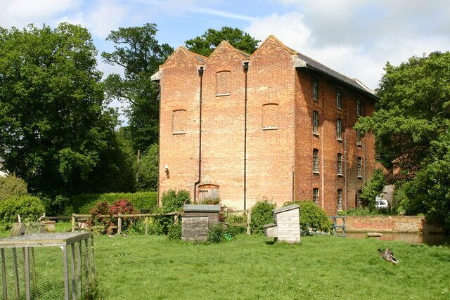 A large brick building with multiple windows and a grassy area in front.