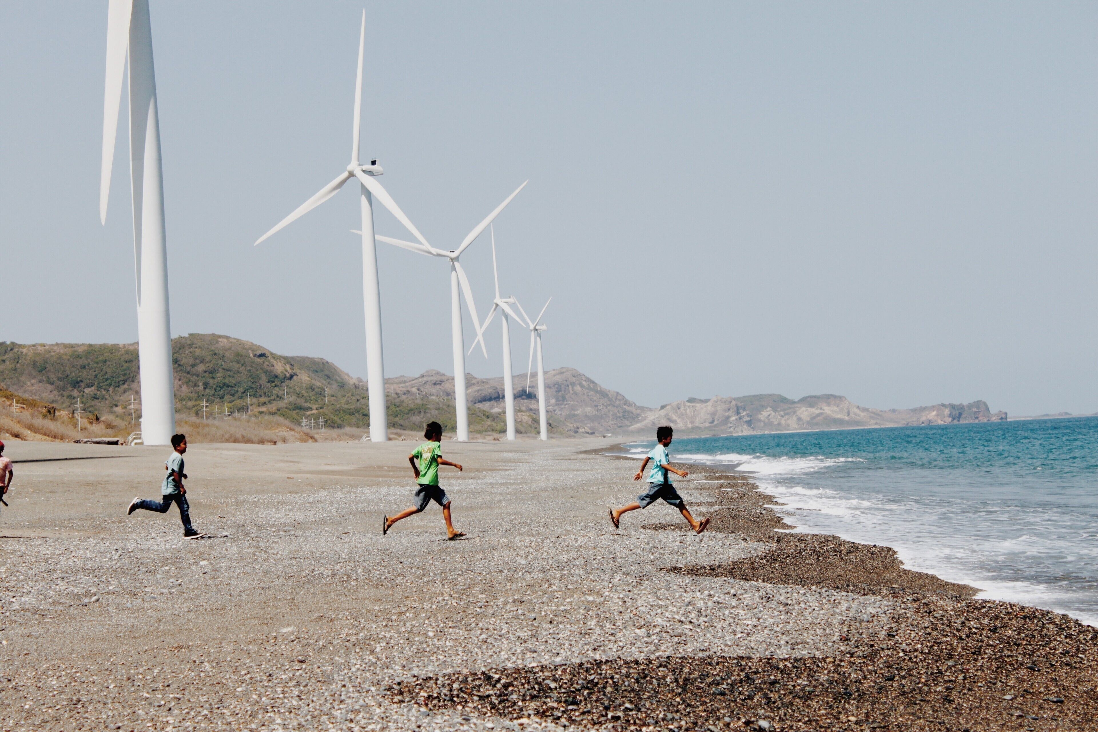A beach with wind turbines in the background.