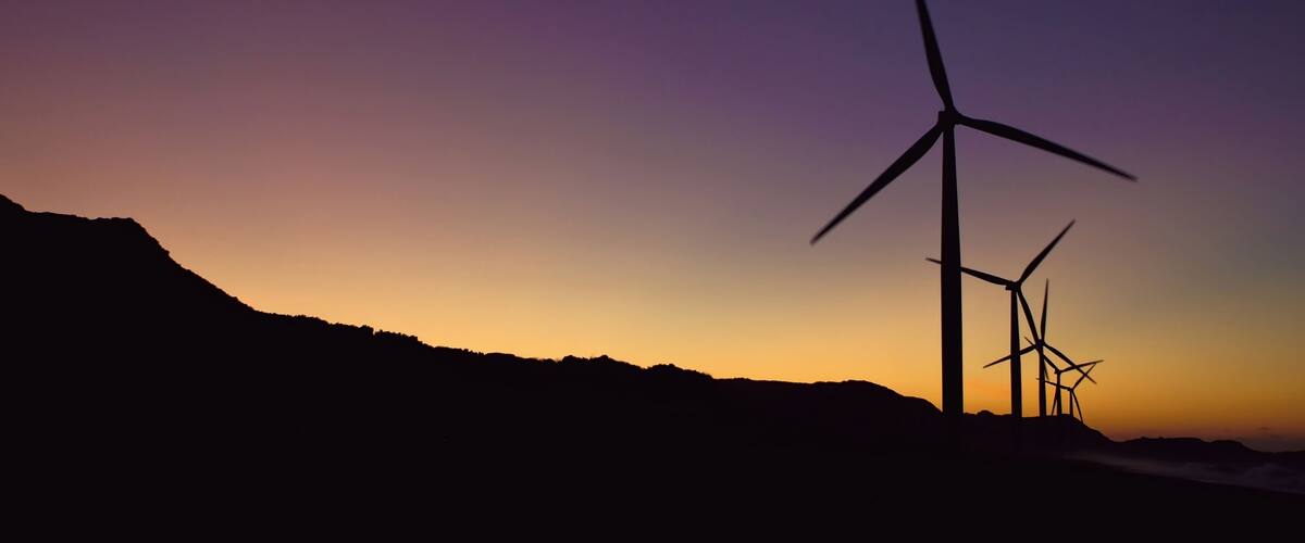 Wind turbines silhouetted against a sunset sky.