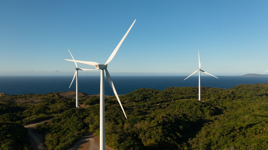 Wind turbines on a coastal landscape with a clear view of the ocean.
