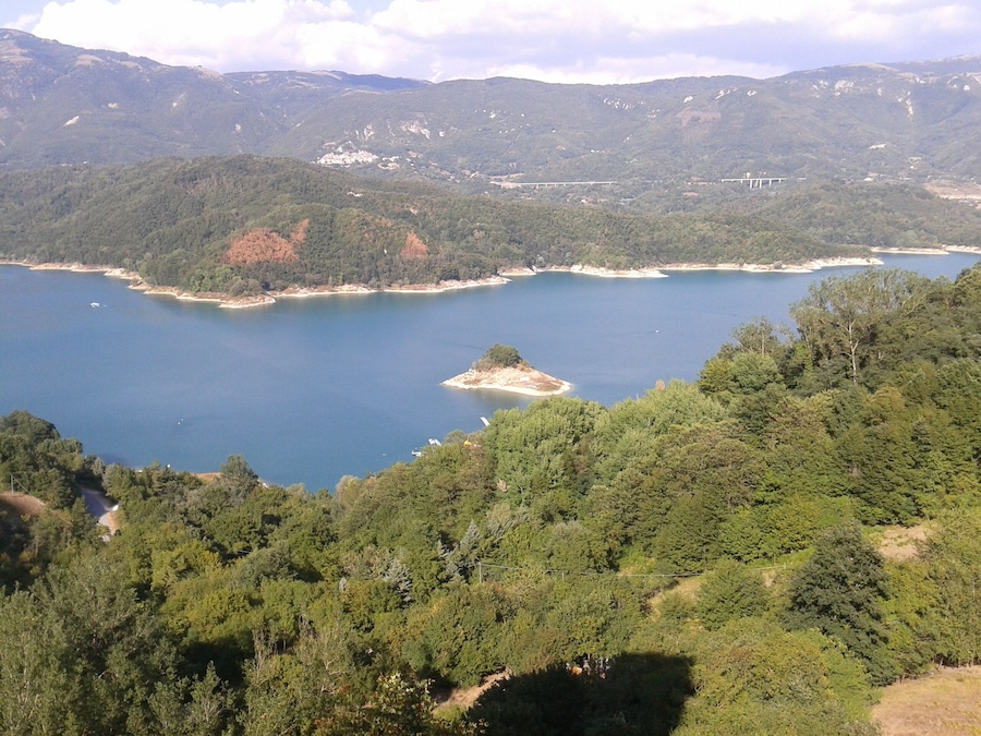 Um lago cercado por floresta densa e montanhas.