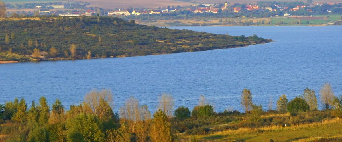 A river with a small island, surrounded by fields and a distant town.