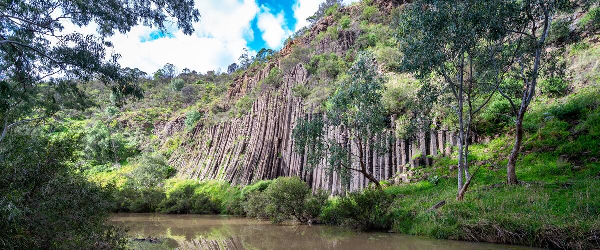 A river with surrounding greenery and a rocky cliff.