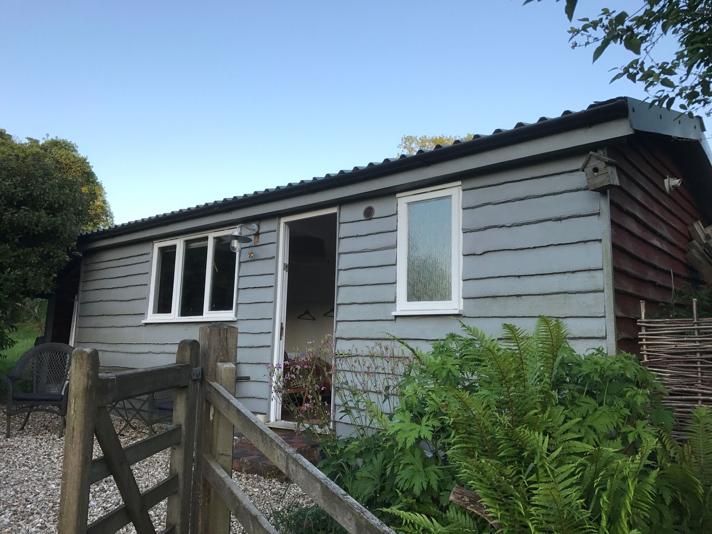 A wooden house with a grey exterior, white trim, and a metal roof.