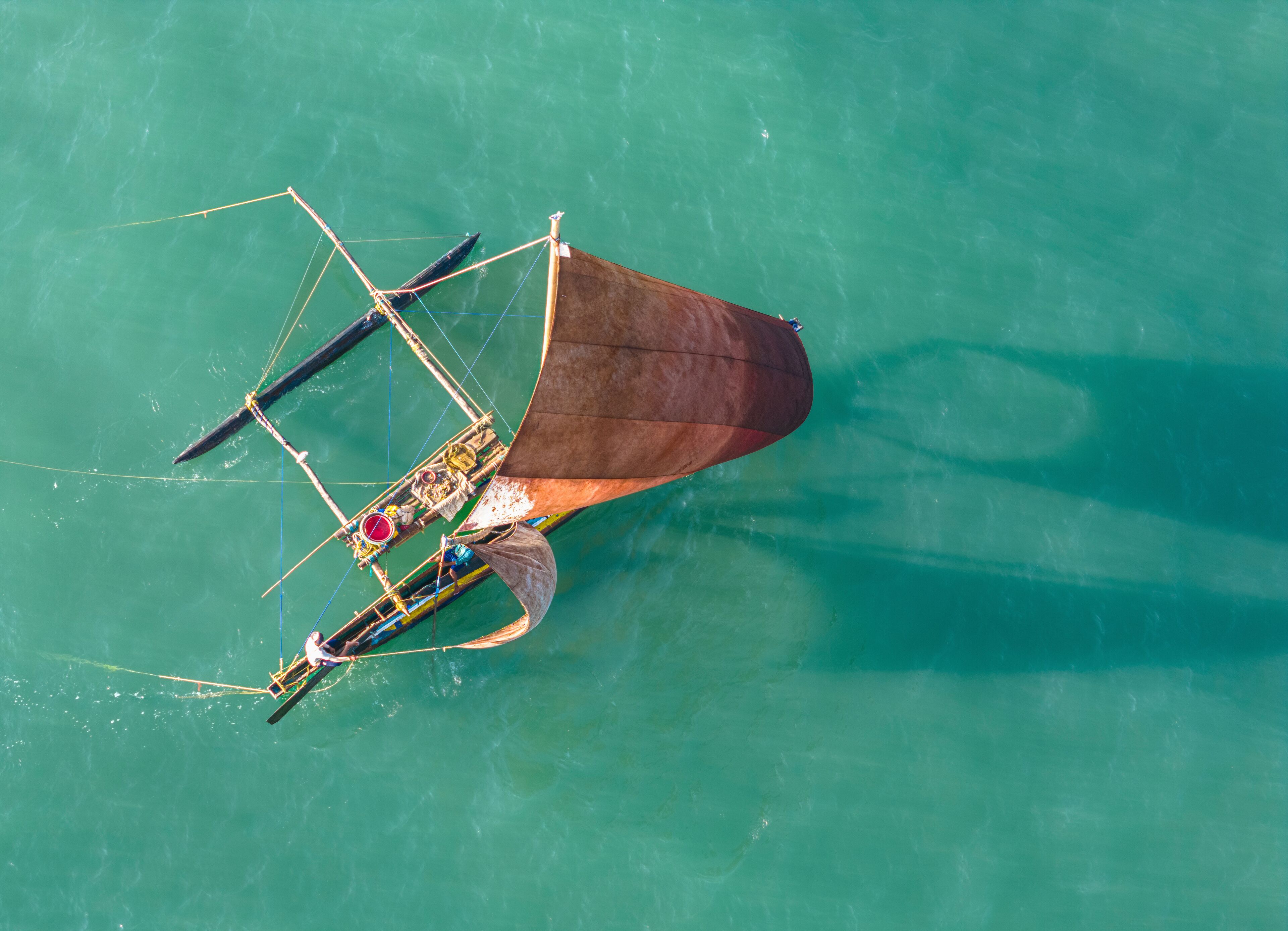 Aerial view of turquoise sea with fishing pirogue, Kochchikade, Sri Lanka.