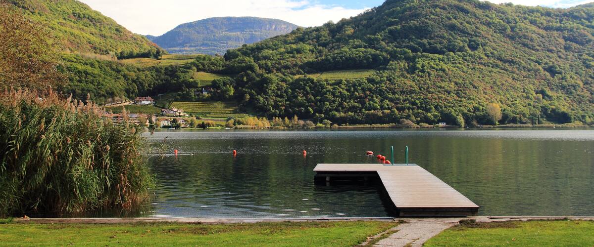 A lake surrounded by hills, a wooden dock, and a distant castle-like structure.