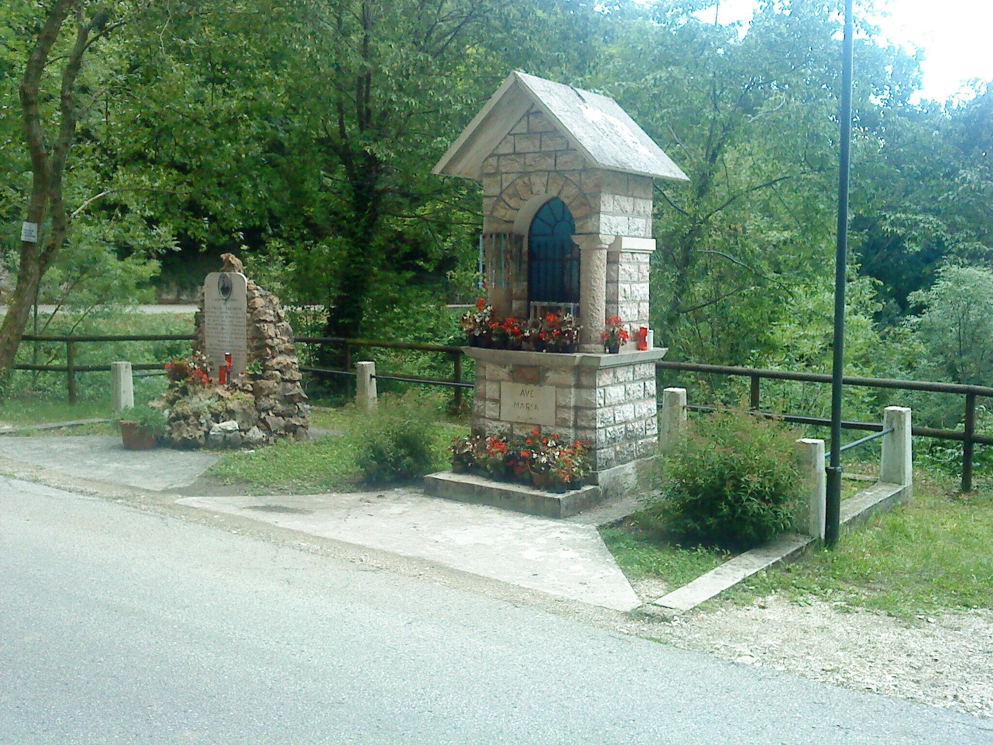 A stone structure with a blue door, surrounded by flowers and greenery.