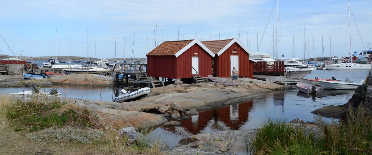 A harbor with boats, a red building, and rocky shores.