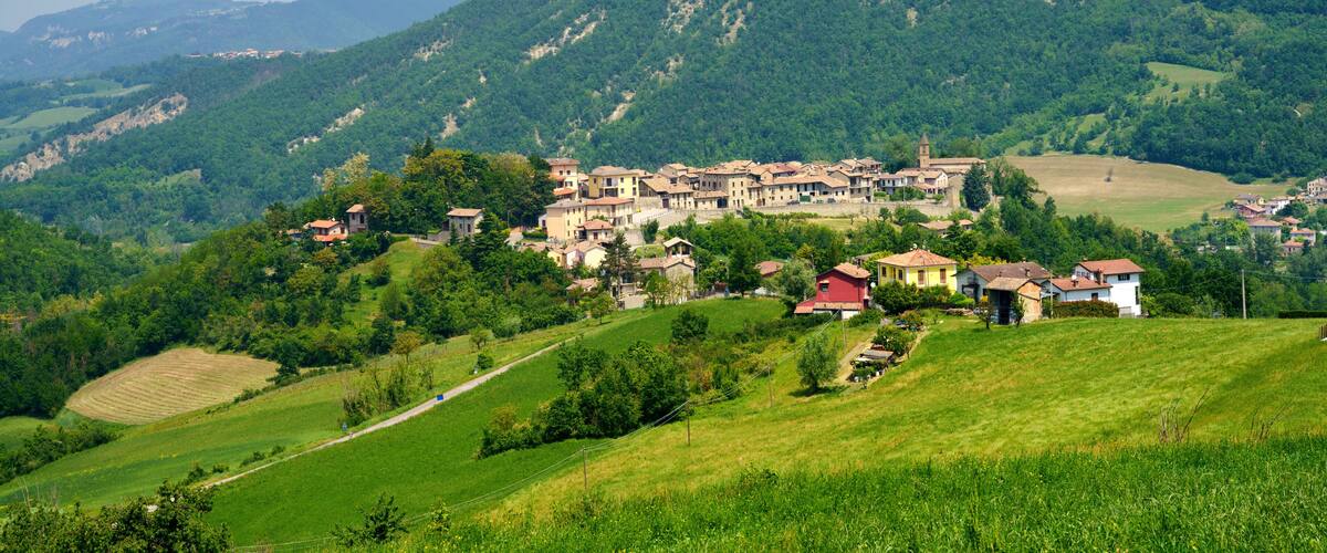 A village nestled in a valley with rolling hills and a church in the background.