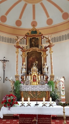 Un altar de iglesia ornamentado con un crucifijo, estatuas y velas.