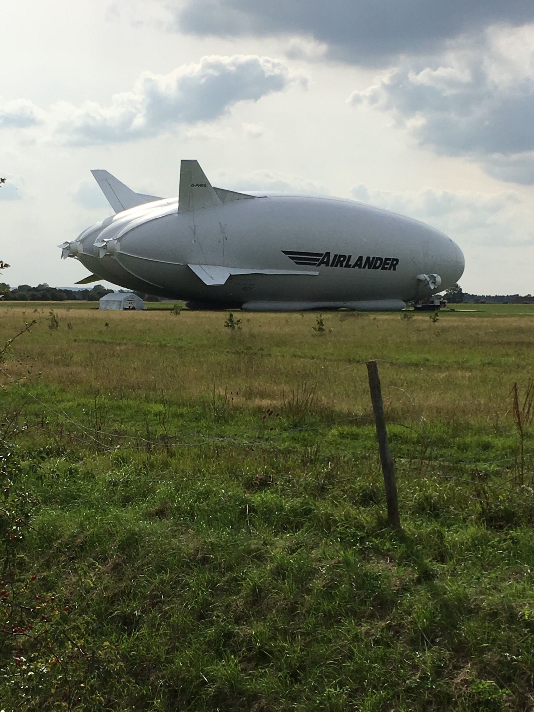 A large blimp with the word "AIRLANDER" on it parked in a grassy field.