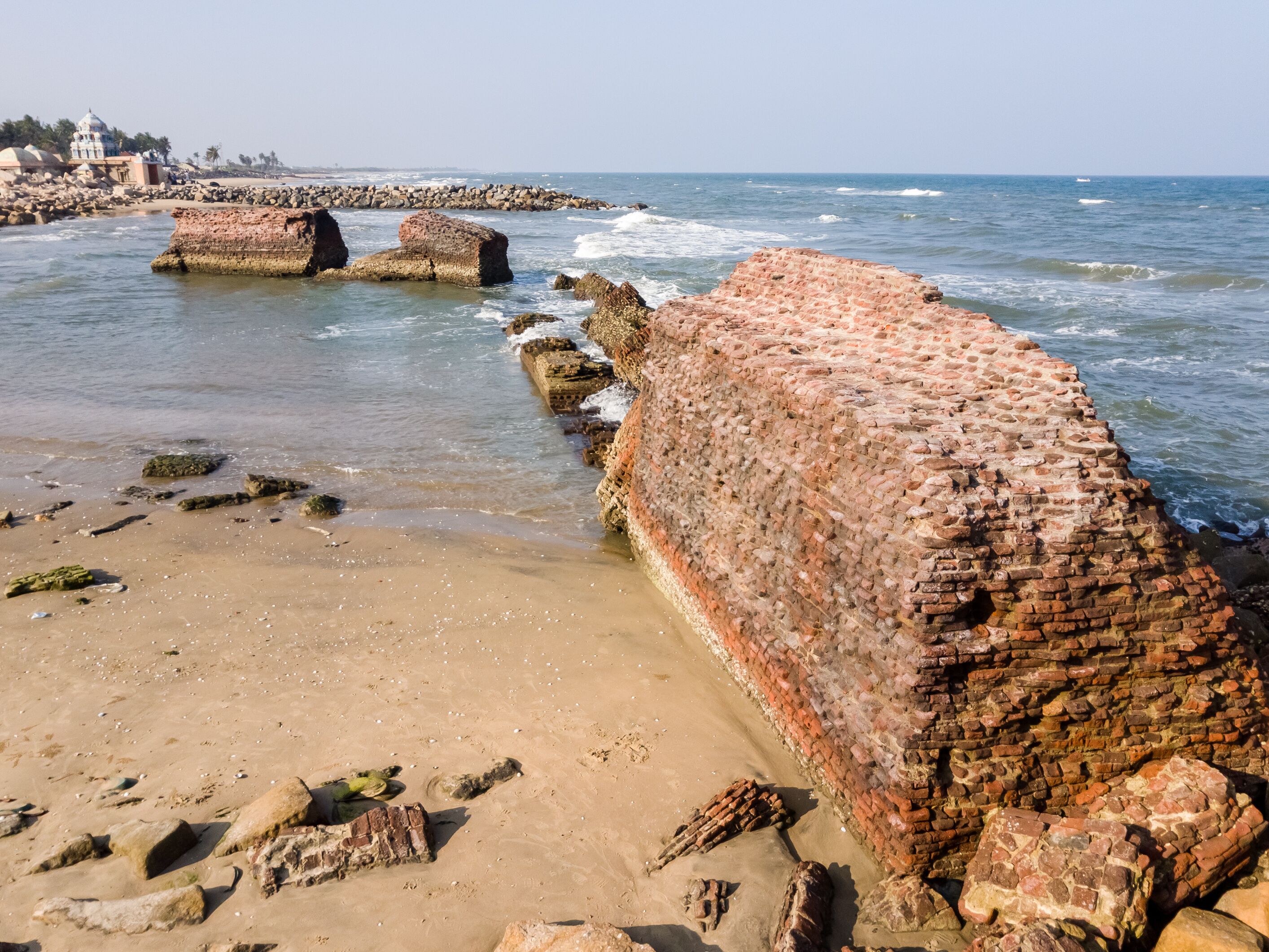 A coastal beach with large, weathered brick walls and scattered rocks.