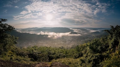 A mountainous landscape with dense forests, a valley, and a sunlit sky.