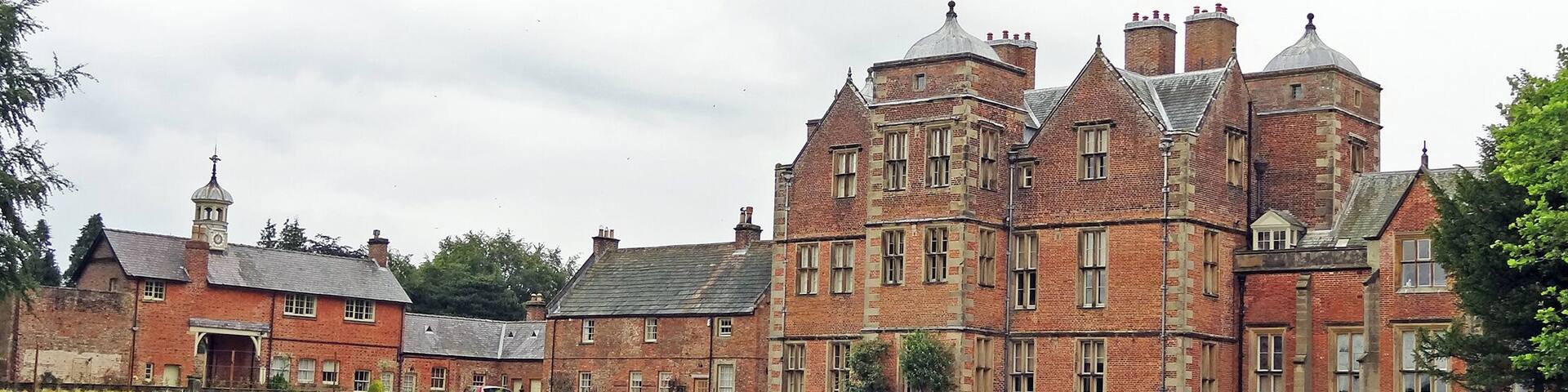 a general view of the back of the Grade I listed Kiplin Hall from beside the lake