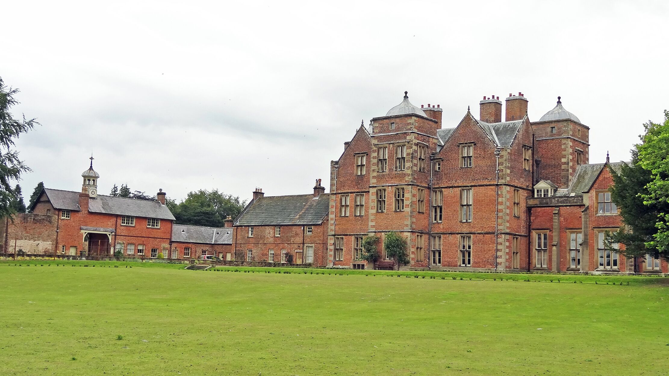 A large, historic brick building with multiple chimneys and a clock tower.