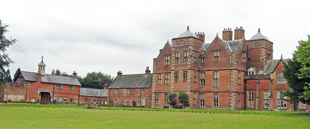 A large, historic brick building with multiple chimneys and a clock tower.