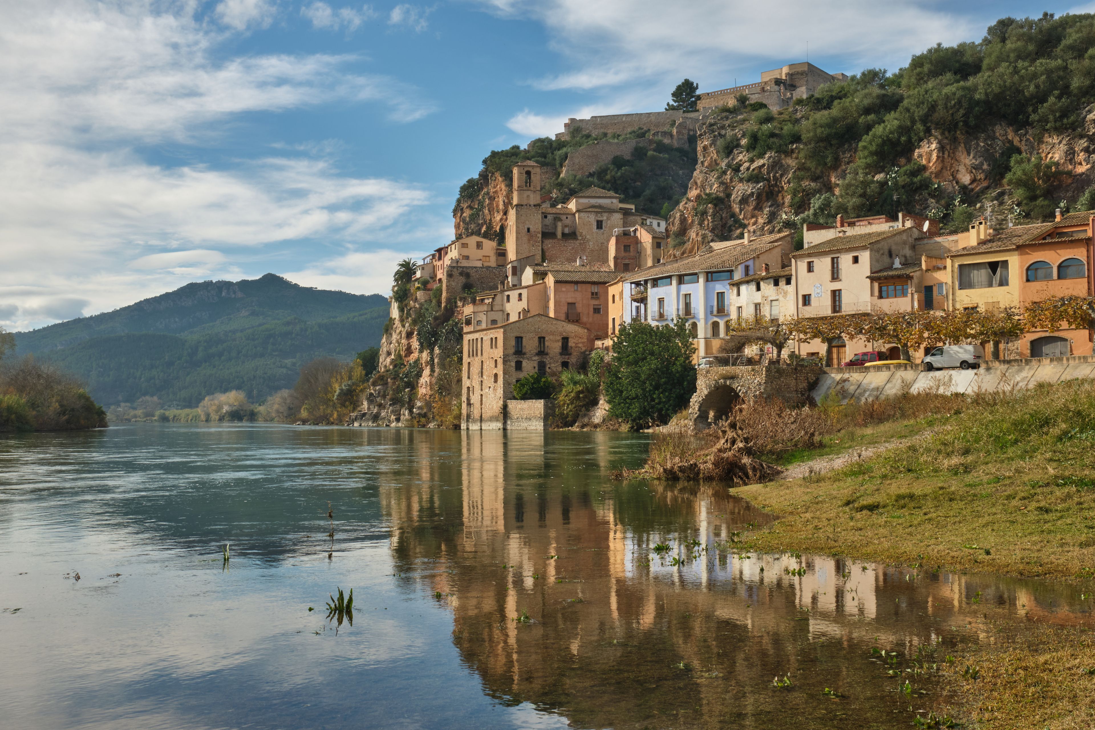 Une ville riveraine dotée de bâtiments historiques, d’une église remarquable et bordée par une montagne en arrière-plan.