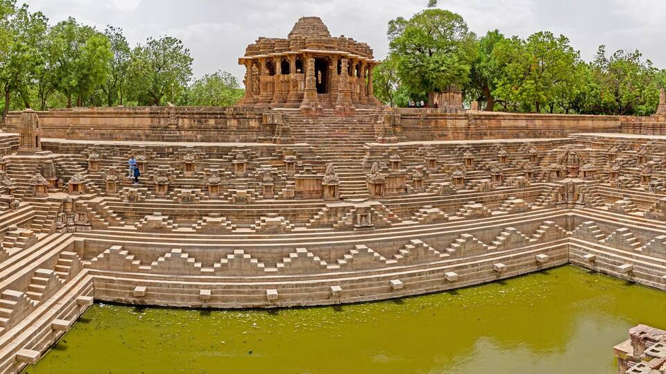 A large ancient temple complex with multiple levels of stone steps and a central water body.