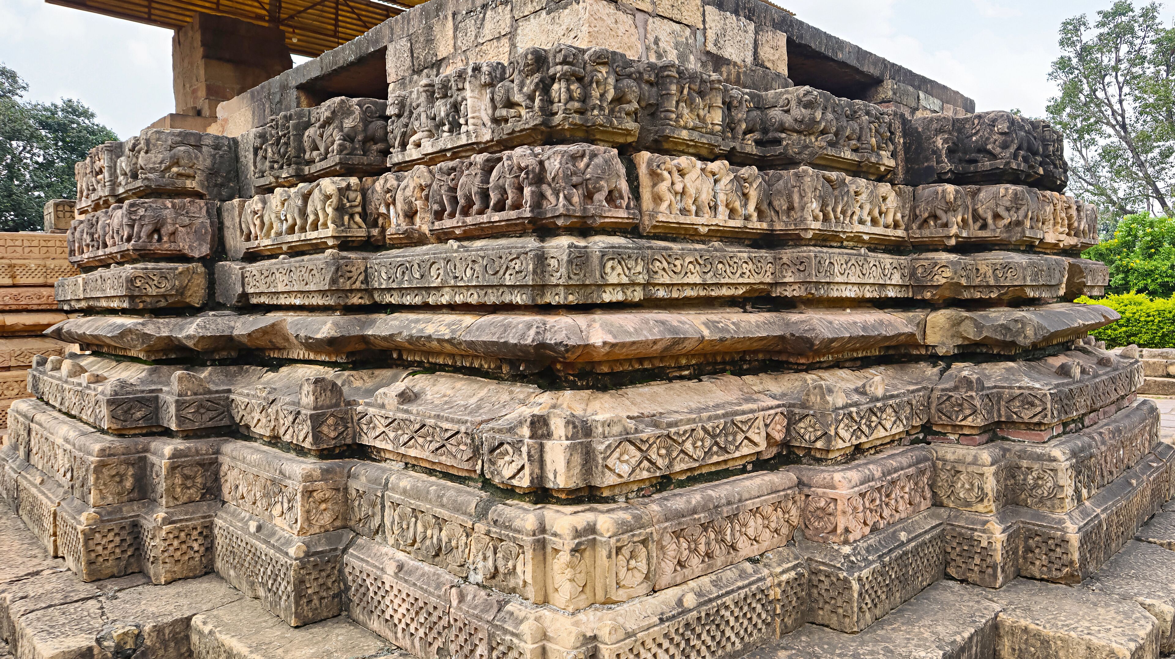 A multi-tiered stone structure with intricate carvings of figures and patterns.