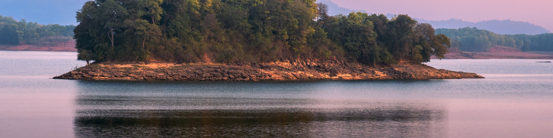 A tranquil lake with a small island covered in trees.
