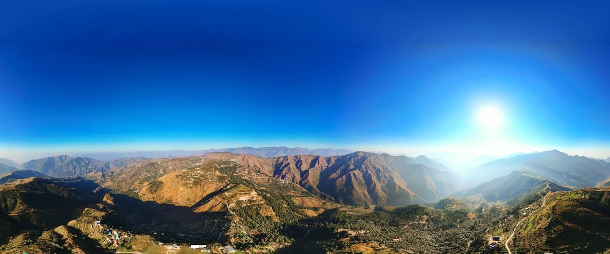 A mountainous landscape with terraced fields and a clear blue sky.