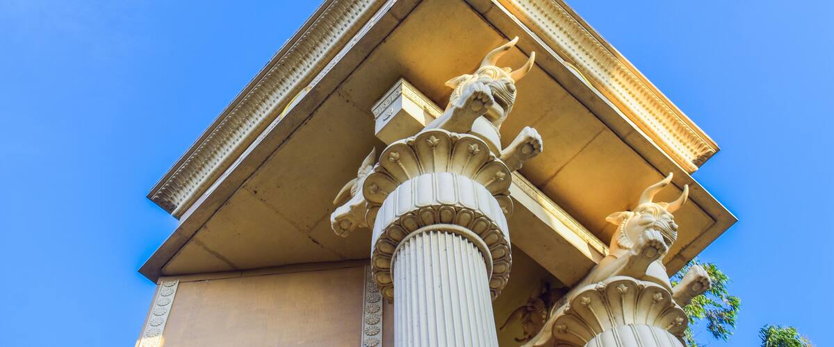 A classical building with ornate columns and a triangular pediment.